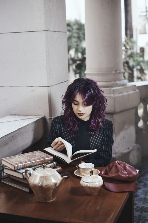 Retrato íntimo y artístico de quinceañera con libros y elementos vintage; fotografía para familias que buscan un estilo europeo y sofisticado en Argentina.
